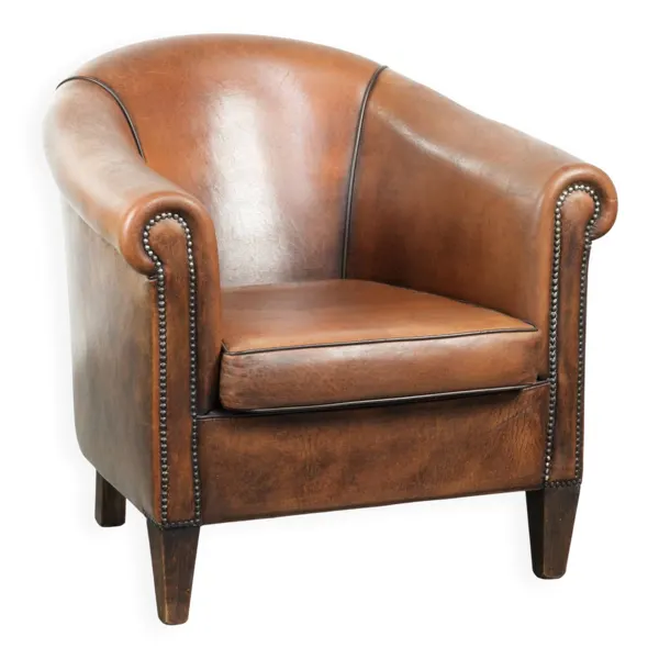 Fauteuil club en peau de mouton avec une belle patine et une finition avec passepoil noir.