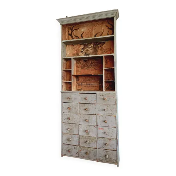 Meuble de métier à tiroirs avec  très ancienne publicité de tabac en fond