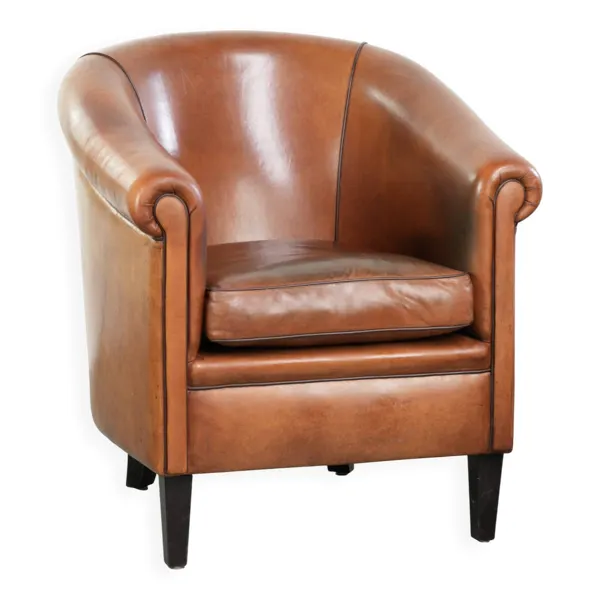 Fauteuil club en peau de mouton vintage avec une palette de couleurs chaudes et des passepoils noirs.