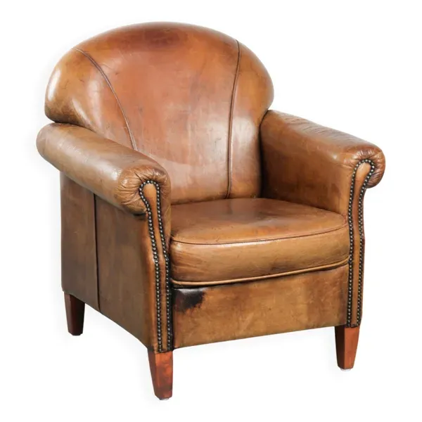 Fauteuil en peau de mouton avec un beau look vintage et une finition cloutée décorative.