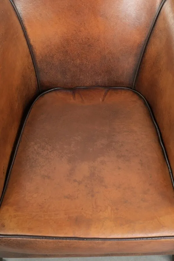 Illustration numéro 2 du produit Fauteuil club en peau de mouton avec une belle patine et une finition avec passepoil noir.