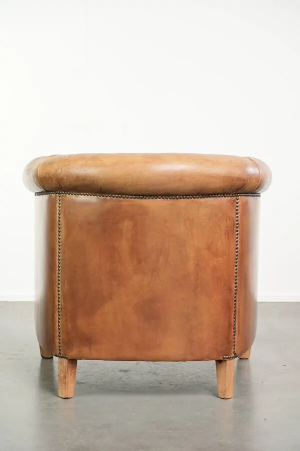 Illustration numéro 2 du produit Fauteuil club en peau de mouton de couleur cognac, fini avec des clous décoratifs.