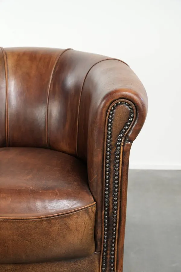 Illustration numéro 2 du produit Fauteuil club en peau de mouton avec une belle patine, fini avec des clous décoratifs.