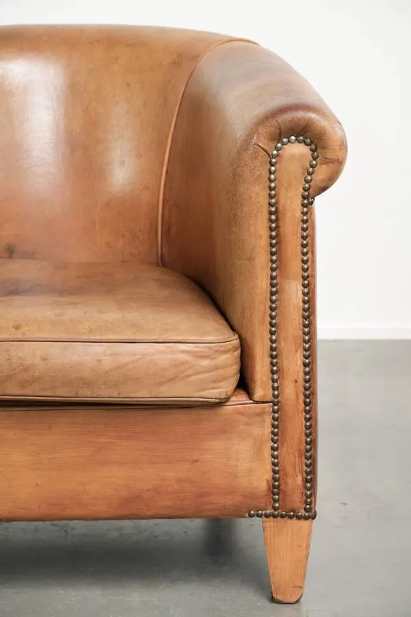 Illustration numéro 3 du produit Fauteuil club en peau de mouton de couleur cognac, fini avec des clous décoratifs.