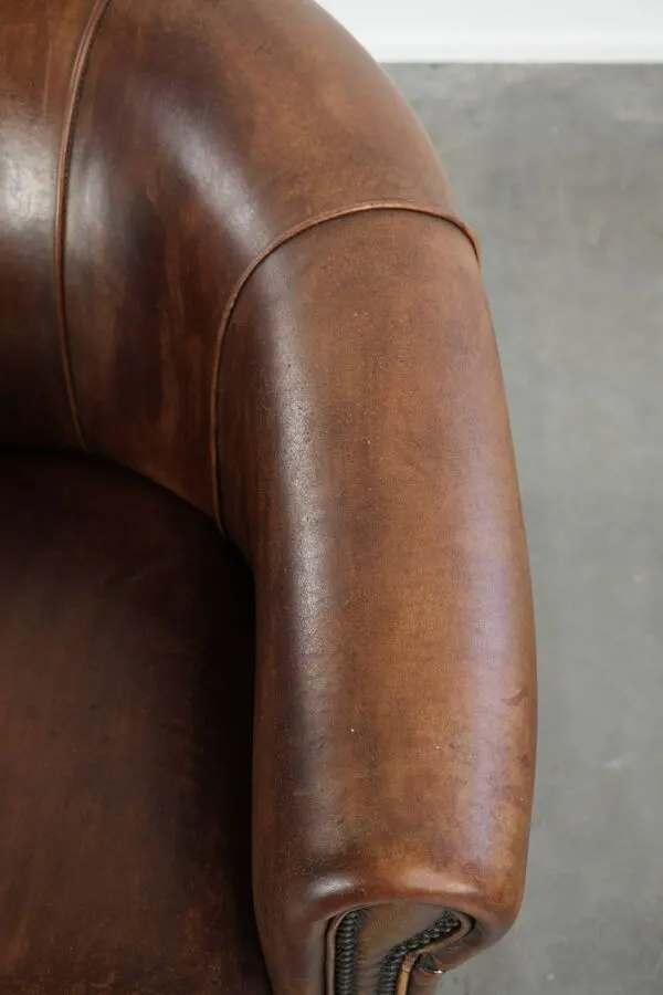 Illustration numéro 3 du produit Fauteuil club en peau de mouton avec une belle patine, fini avec des clous décoratifs.