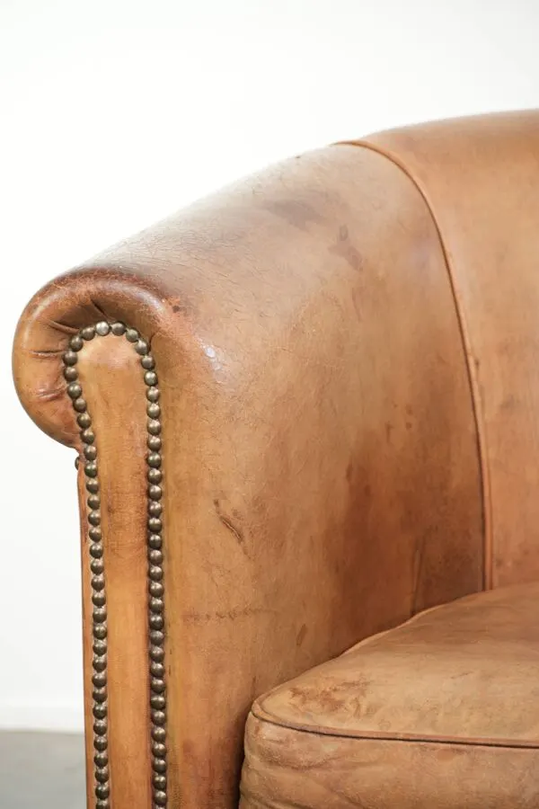 Illustration numéro 5 du produit Fauteuil club en peau de mouton de couleur cognac, fini avec des clous décoratifs.